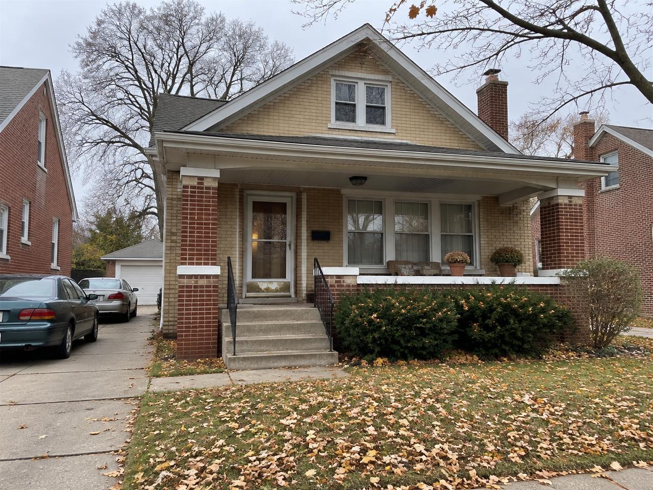 Inherited Detroit brick bungalow with autumn leaves in the front yard